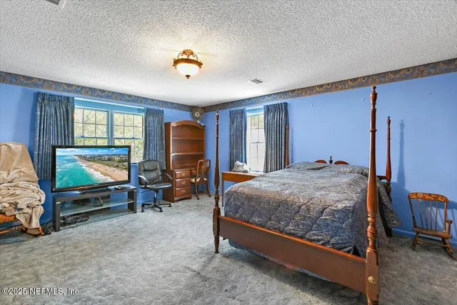 a bedroom with a bed and a flat tv screen on dresser