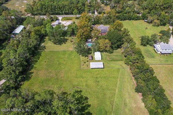 an aerial view of residential house with outdoor space and trees all around
