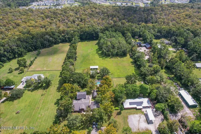 an aerial view of residential house with outdoor space and trees all around