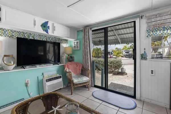 a living room with furniture a flat screen tv and a floor to ceiling window