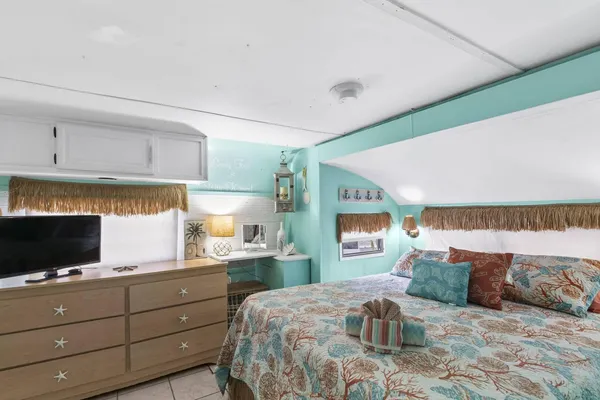a bedroom with a large bed and a flat tv screen on dresser