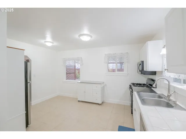 a kitchen with stainless steel appliances a sink a stove a refrigerator cabinets and a window