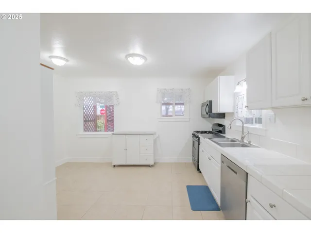a kitchen with white cabinets stainless steel appliances and sink