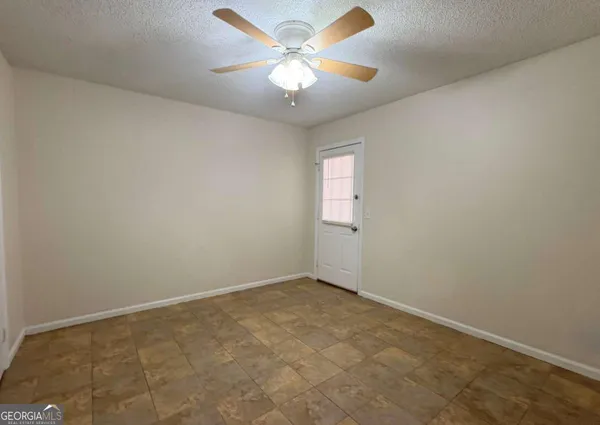 an empty room with windows and fan