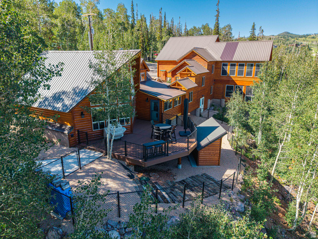 401 North Aoki Michi Road Brian Head, UT 84719 - Photo 3 of 58 Wood-sided exterior featuring multiple structures, a spacious deck, metal roofing, and a gravel perimeter with fencing