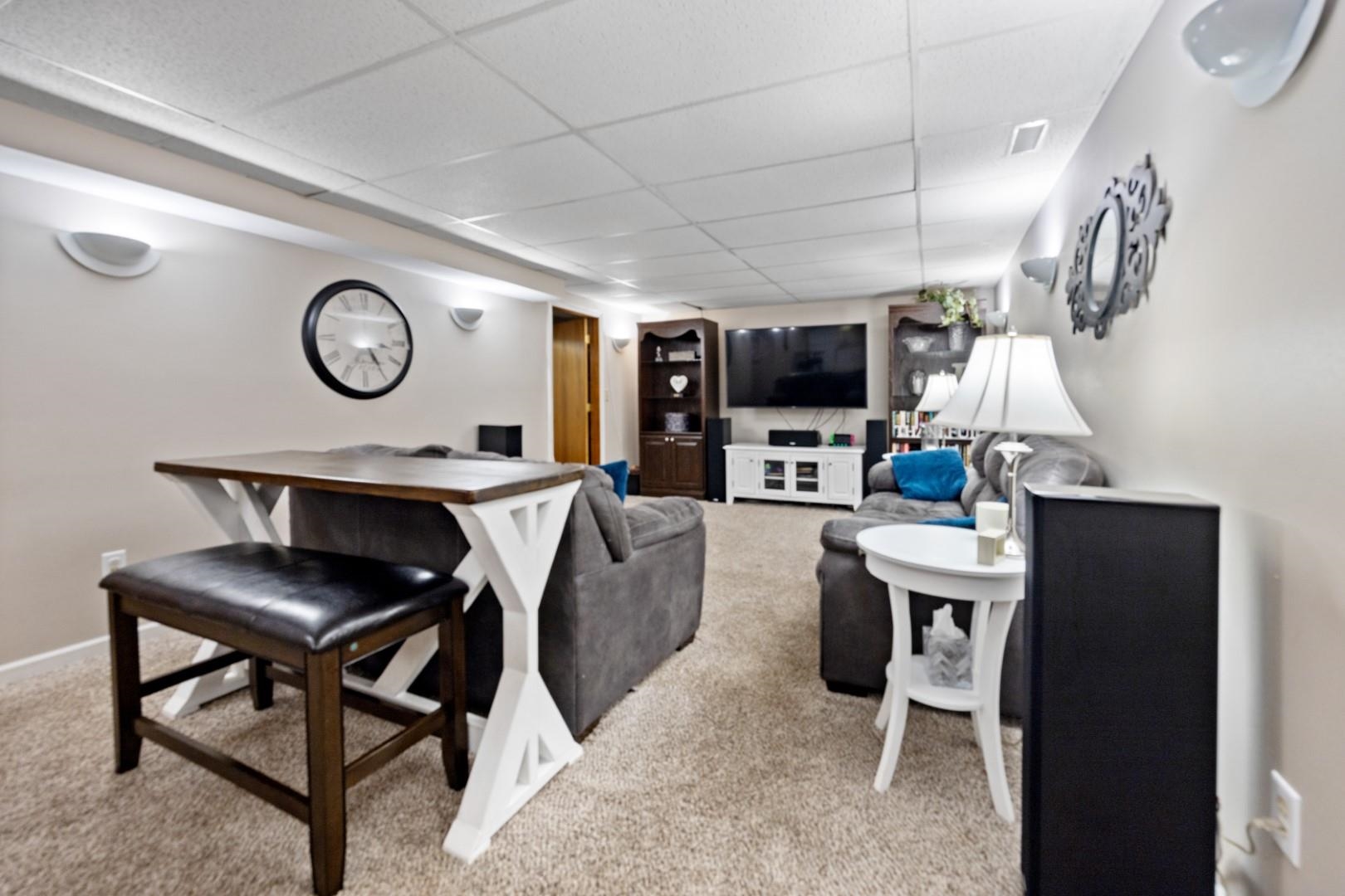 5568 Gray Eagle Road Roscoe, IL 61073 - Photo 26 of 45 a living room with furniture a clock and a flat screen tv