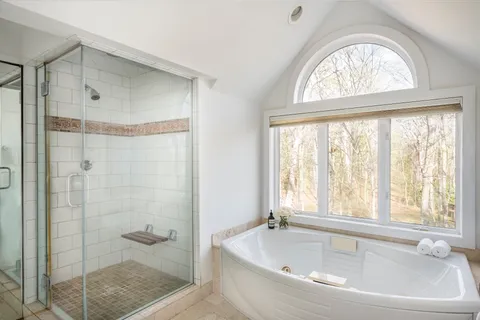 a bathroom with a tub shower and window