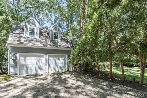 a front view of a house with a garden and trees