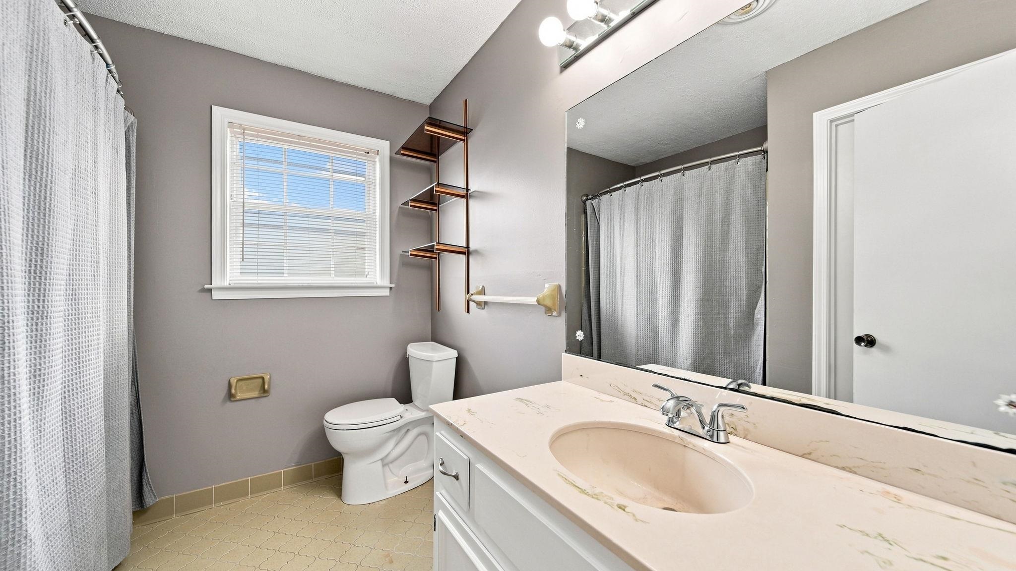 4920 Whitworth Road Memphis, TN 38116 - Photo 18 of 32 Bathroom featuring a vanity with an integrated sink, a large mirror, a window with blinds, and built-in shelving