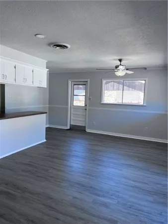 an empty room with wooden floor chandelier and windows