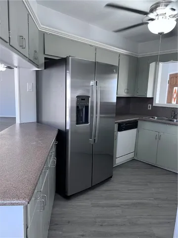 a kitchen with kitchen island granite countertop a sink and refrigerator