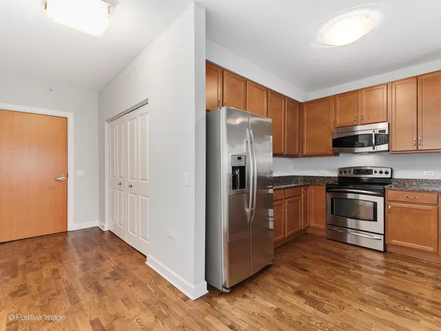 a kitchen with granite countertop a refrigerator and a stove top oven