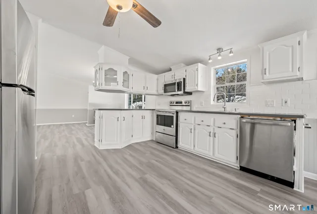 a view of a livingroom with furniture wooden floor chandelier and windows