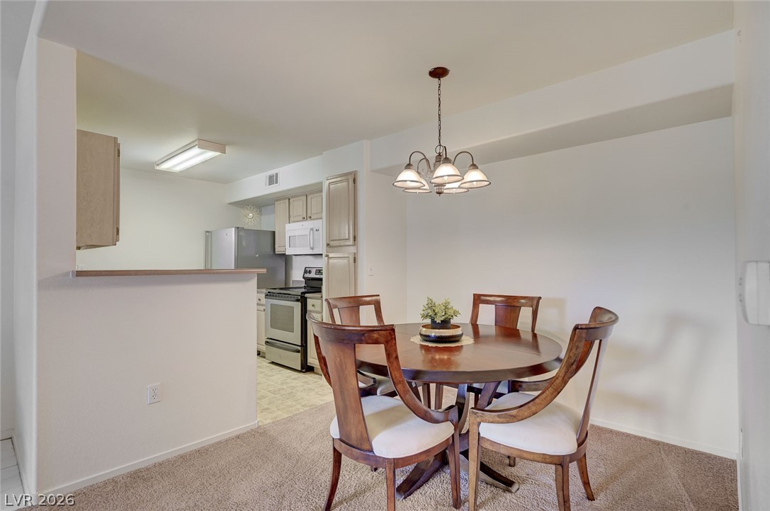 555 East Silverado Ranch Boulevard, Unit 2124 Las Vegas, NV 89183 - Photo 12 of 47 A classic chandelier illuminates the dining area, seamlessly connecting to the kitchen.