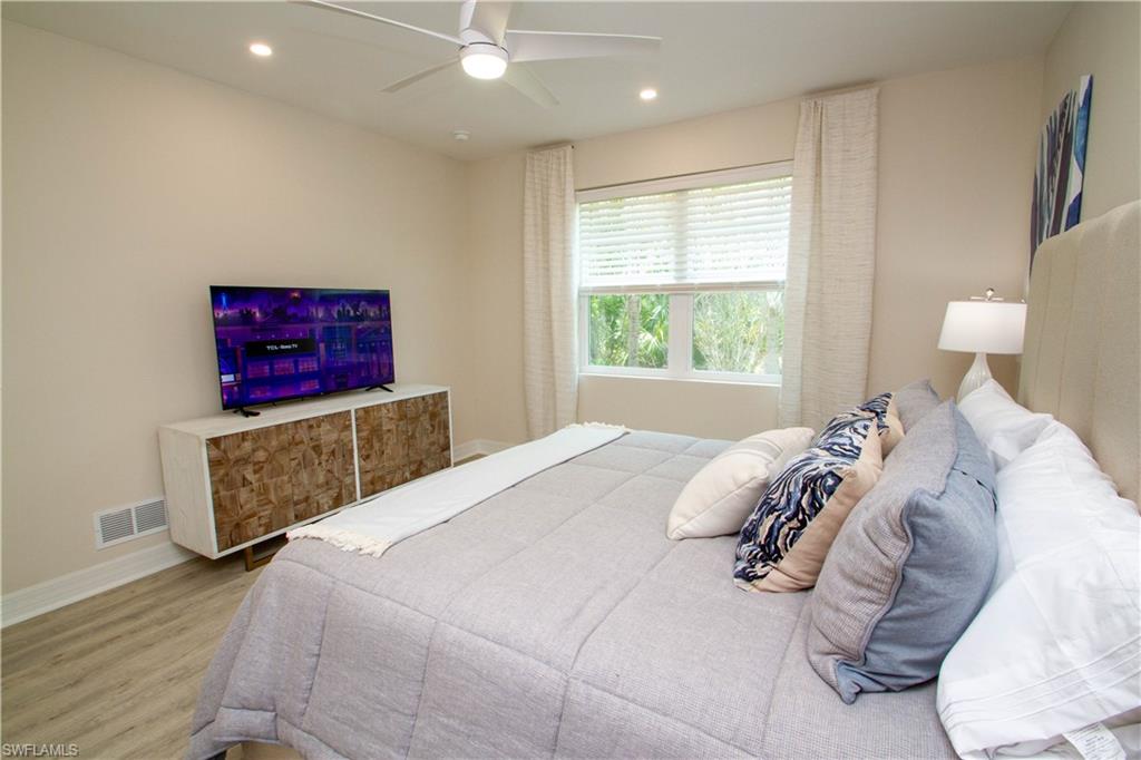 268 Indies Drive East, Unit 102 Naples, FL 34114 - Photo 22 of 48 a bedroom with a bed and a painting on the wall