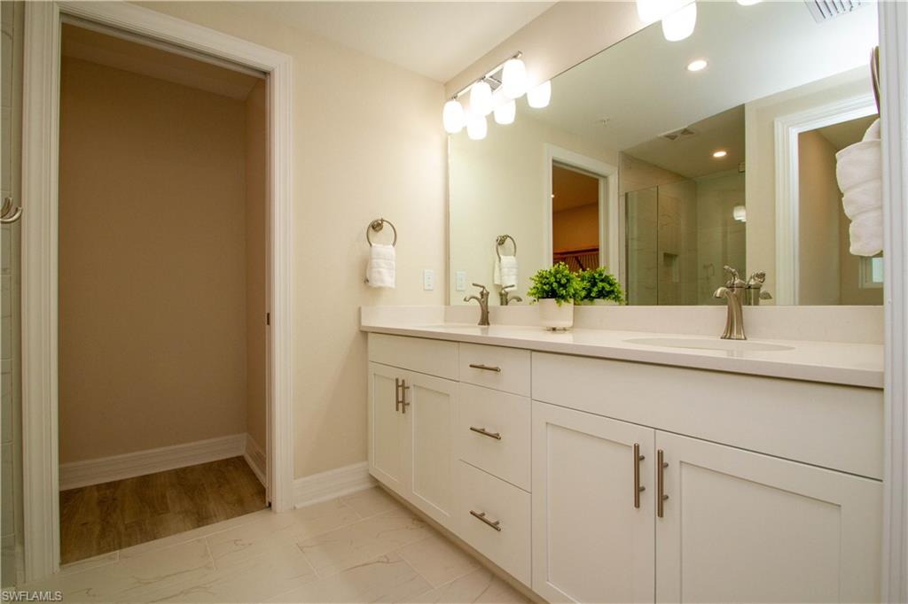 268 Indies Drive East, Unit 102 Naples, FL 34114 - Photo 23 of 48 a bathroom with a double vanity sink and a mirror