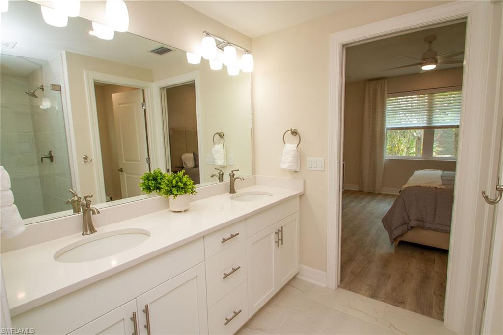 268 Indies Drive East, Unit 102 Naples, FL 34114 - Photo 24 of 48 a en suite bathroom with double sink and a large mirror