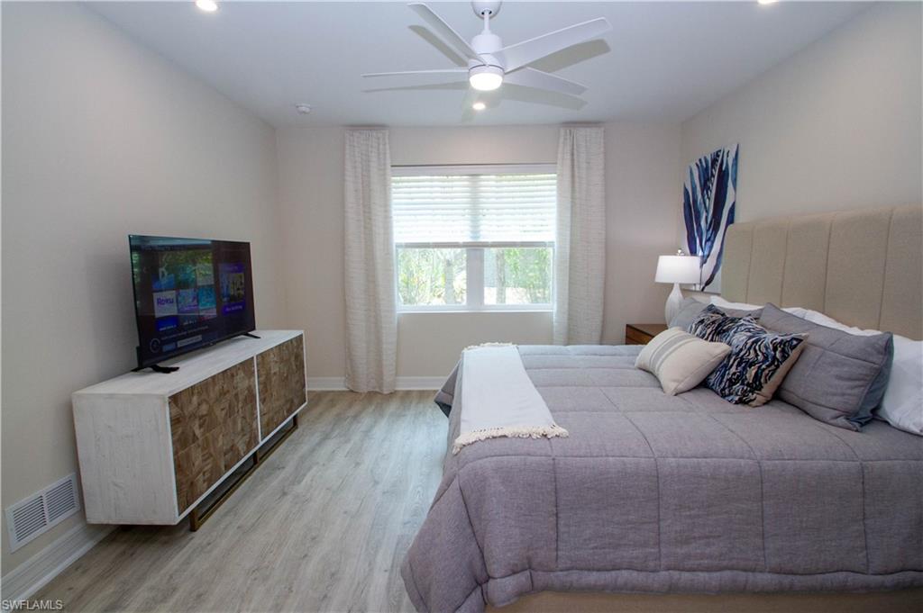 268 Indies Drive East, Unit 102 Naples, FL 34114 - Photo 26 of 48 a bedroom with a bed and a flat screen tv