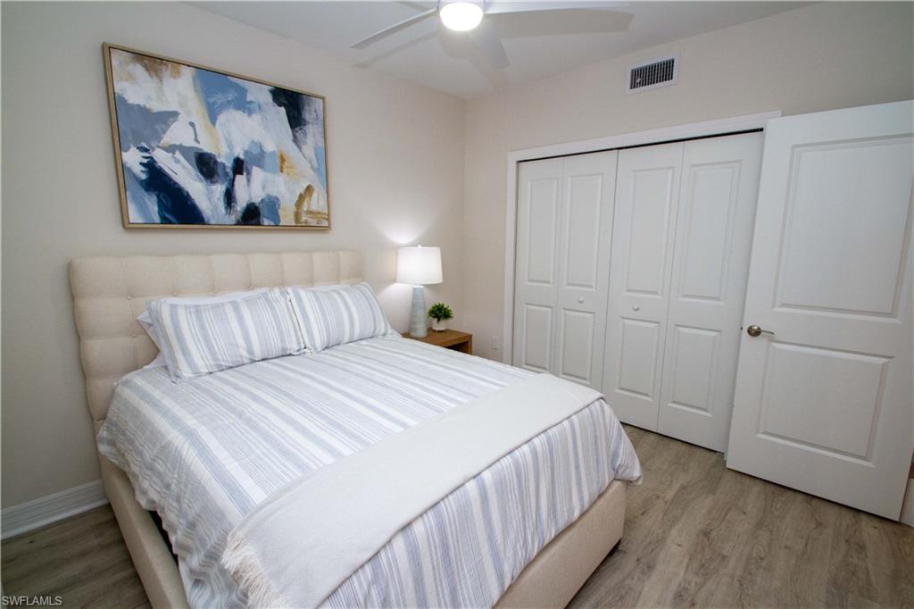 268 Indies Drive East, Unit 102 Naples, FL 34114 - Photo 28 of 48 a bedroom with a bed and a painting on the wall