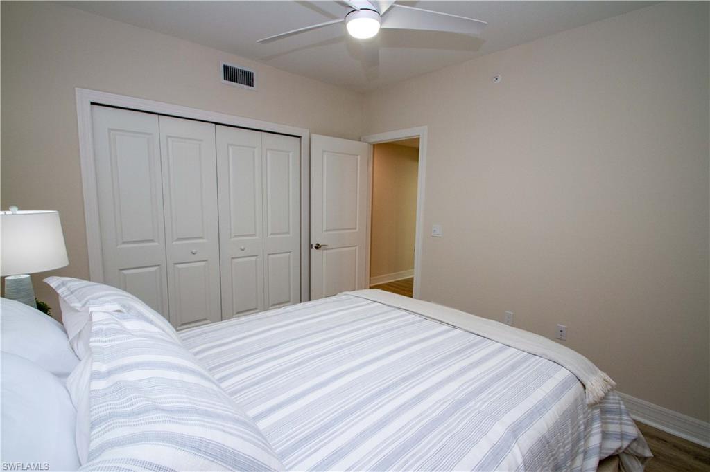 268 Indies Drive East, Unit 102 Naples, FL 34114 - Photo 29 of 48 a bedroom with a bed and a chandelier