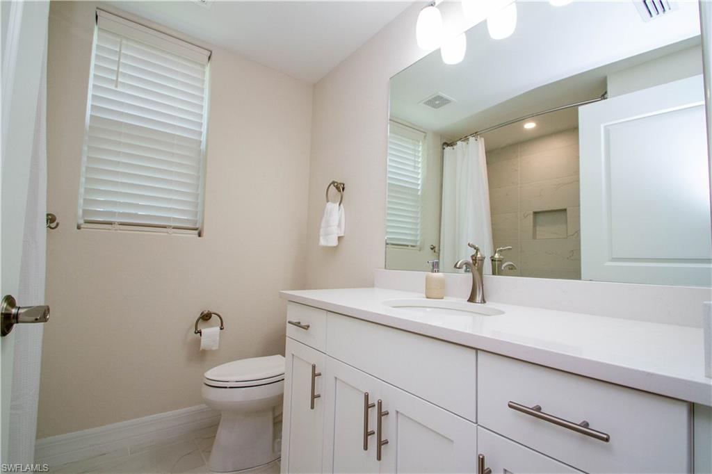 268 Indies Drive East, Unit 102 Naples, FL 34114 - Photo 30 of 48 a bathroom with a toilet a sink a mirror and vanity