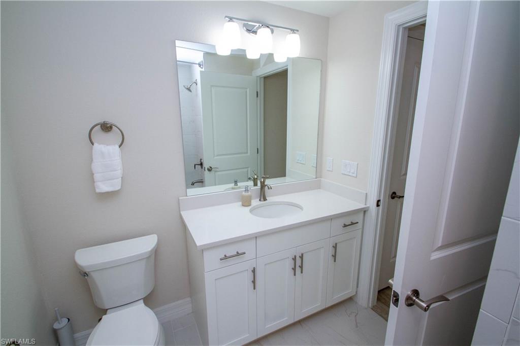 268 Indies Drive East, Unit 102 Naples, FL 34114 - Photo 31 of 48 a bathroom with a toilet sink and mirror