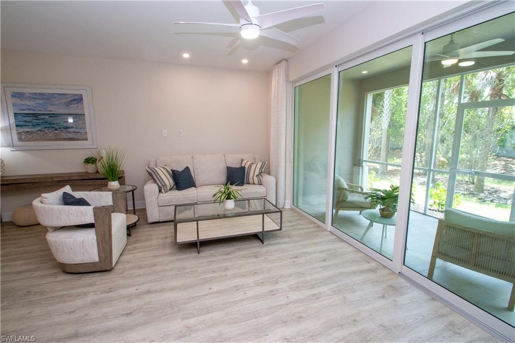 268 Indies Drive East, Unit 102 Naples, FL 34114 - Photo 7 of 48 a living room with furniture and large windows