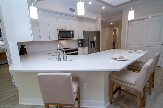 a kitchen with stainless steel appliances a white table chairs and a refrigerator