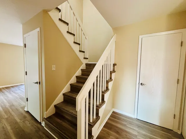 a view of staircase with wooden floor and white walls