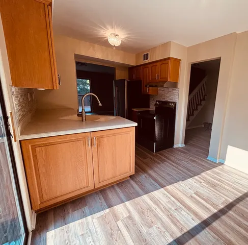 a kitchen with a sink a refrigerator and wooden cabinets