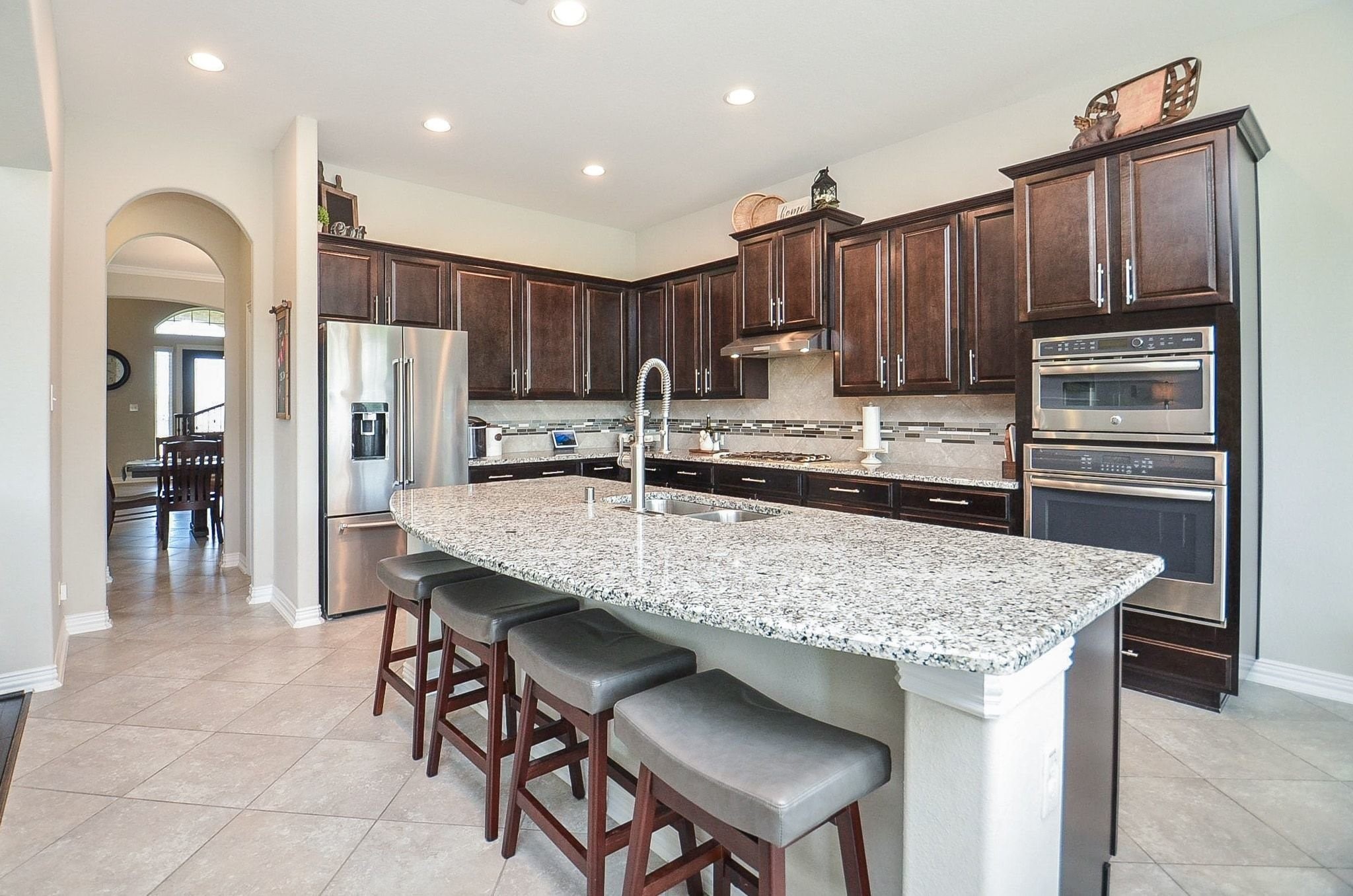 2714 Topaz Cove Lane Rosharon, TX 77583 - Photo 16 of 50 a kitchen with kitchen island granite countertop wooden cabinets a sink and stainless steel appliances