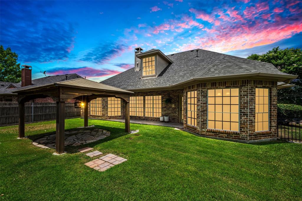 5607 Ranger Drive Rockwall, TX 75032 - Photo 2 of 40 Expansive rear yard featuring a wooden gazebo with a stone patio, a manicured lawn, and a brick-built exterior with multiple bay windows