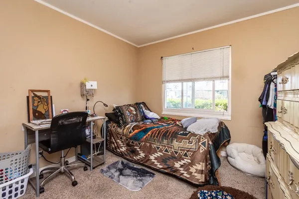 a bedroom with a bed a desk and chair with the wooden floor