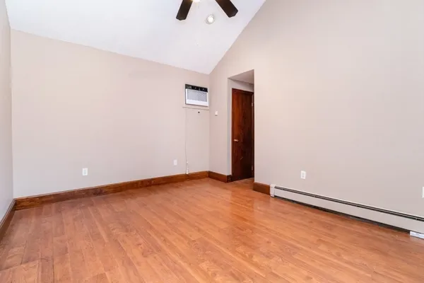 a view of an empty room with wooden floor and a window