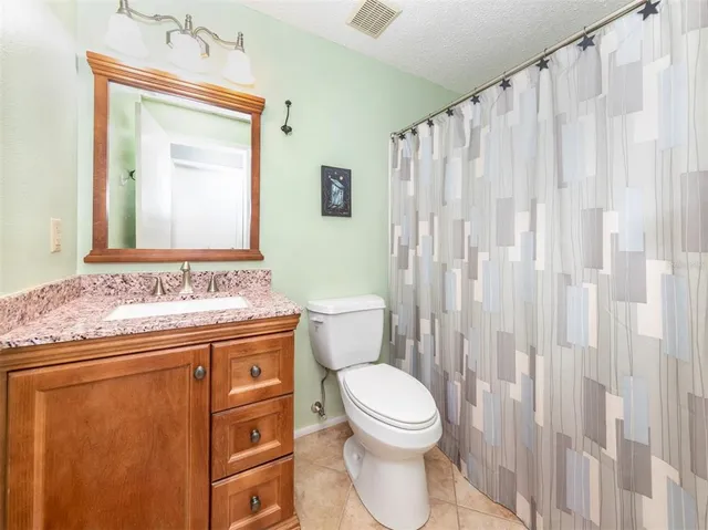 a bathroom with a granite countertop sink a toilet and a mirror