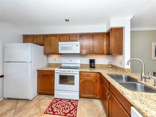 a kitchen with stainless steel appliances granite countertop a refrigerator sink stove and oven