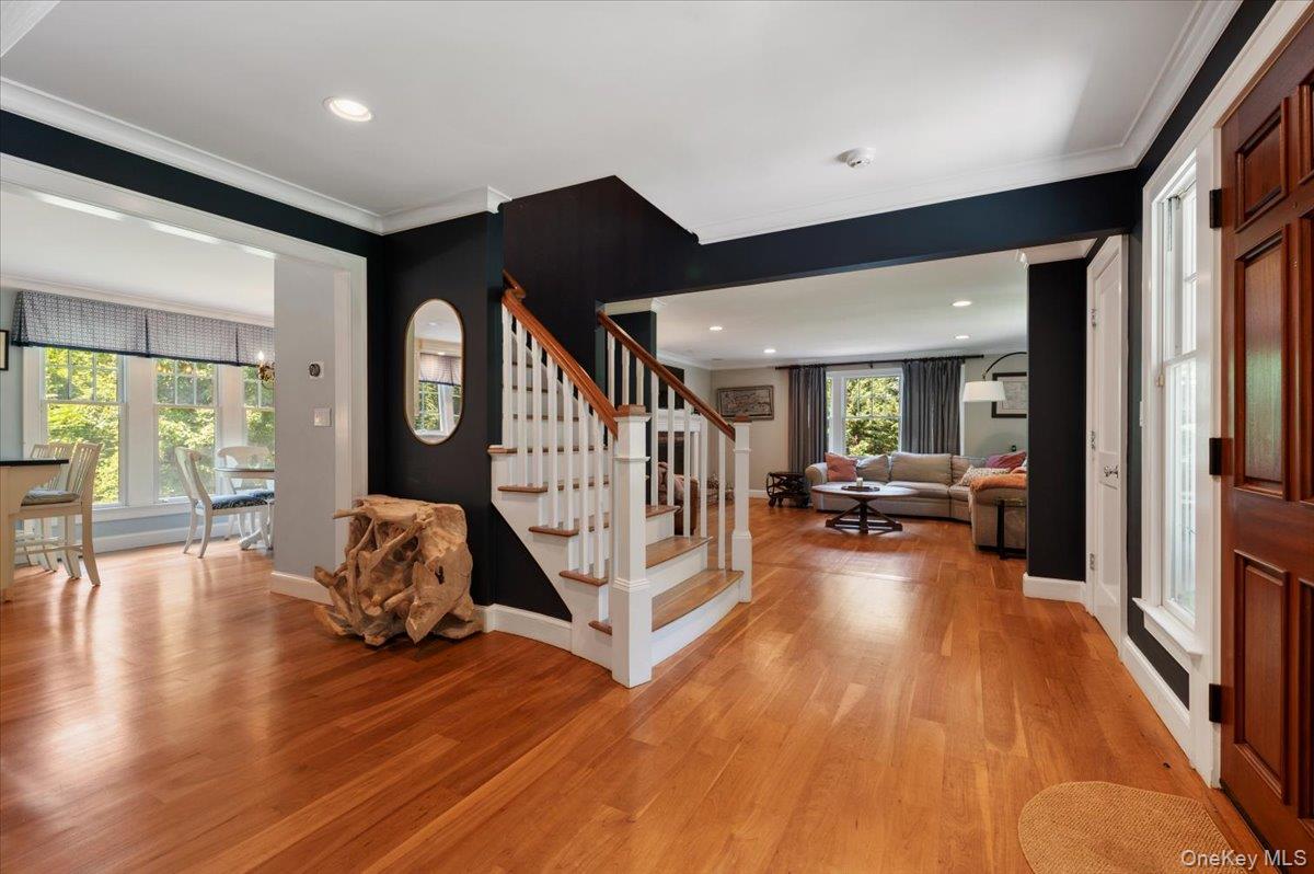 5 Fox Hunt Court Cold Spring Harbor, NY 11724 - Photo 9 of 42 Entryway featuring wood-finish flooring, a staircase with white risers and wood-finish treads, and a paneled front door with sidelight windows