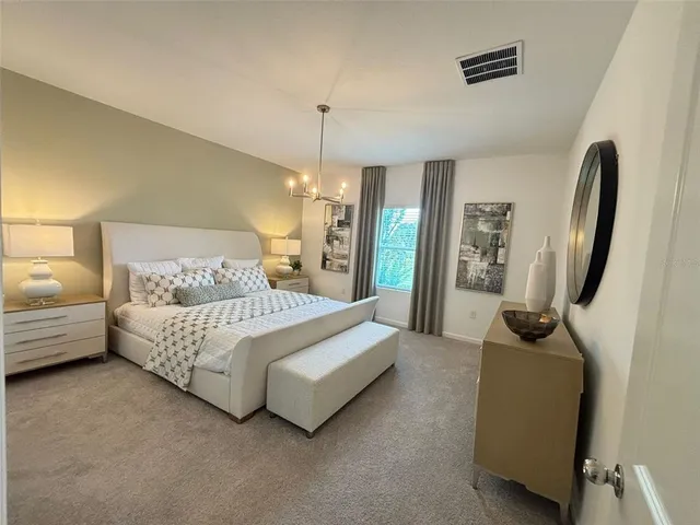 a spacious bedroom with a bed a couch and a chandelier