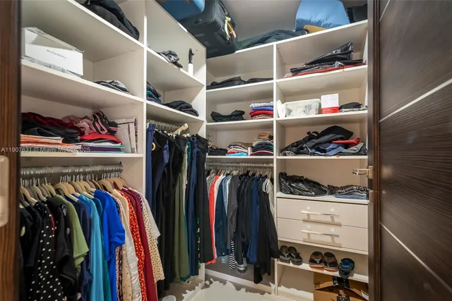 a view of walk in closet with clothes and shoes