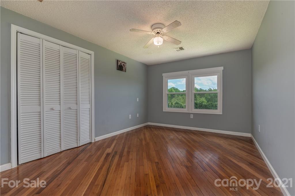 606 Old Stonecutter Road Rutherfordton, NC 28139 - Photo 11 of 48 an empty room with wooden floor chandelier fan and windows