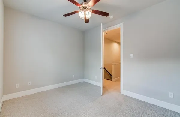 an empty room with chandelier fan and windows