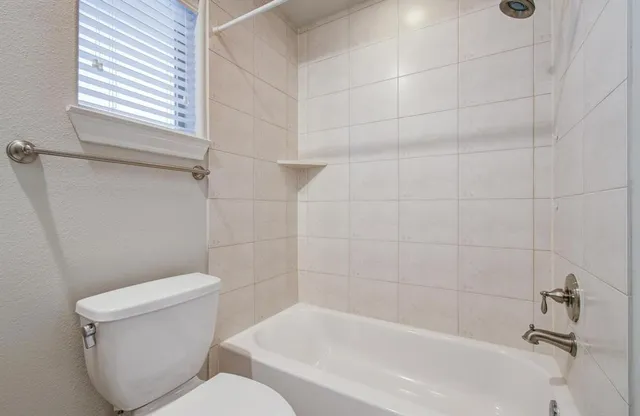 a white toilet sitting next to a bath tub and a shower