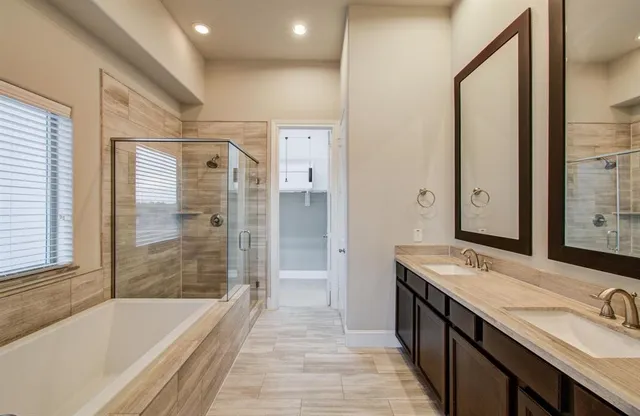 a bathroom with a tub sink shower and two mirror