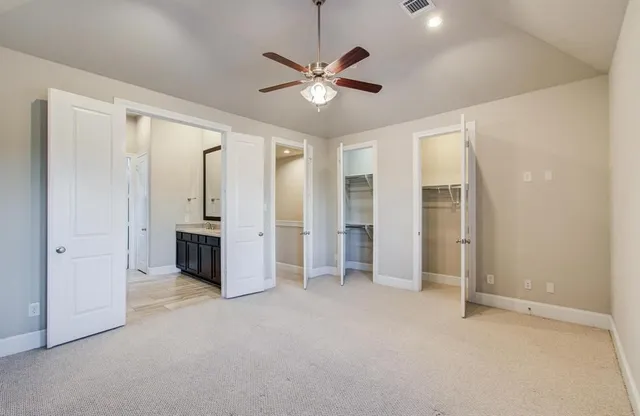 an empty room with closet and a ceiling fan