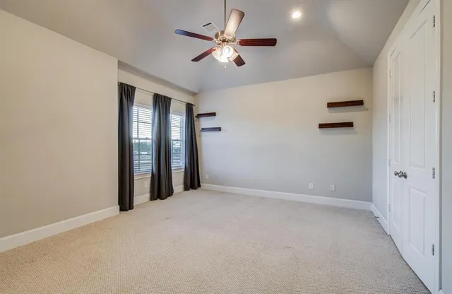 an empty room with closet and ceiling fan