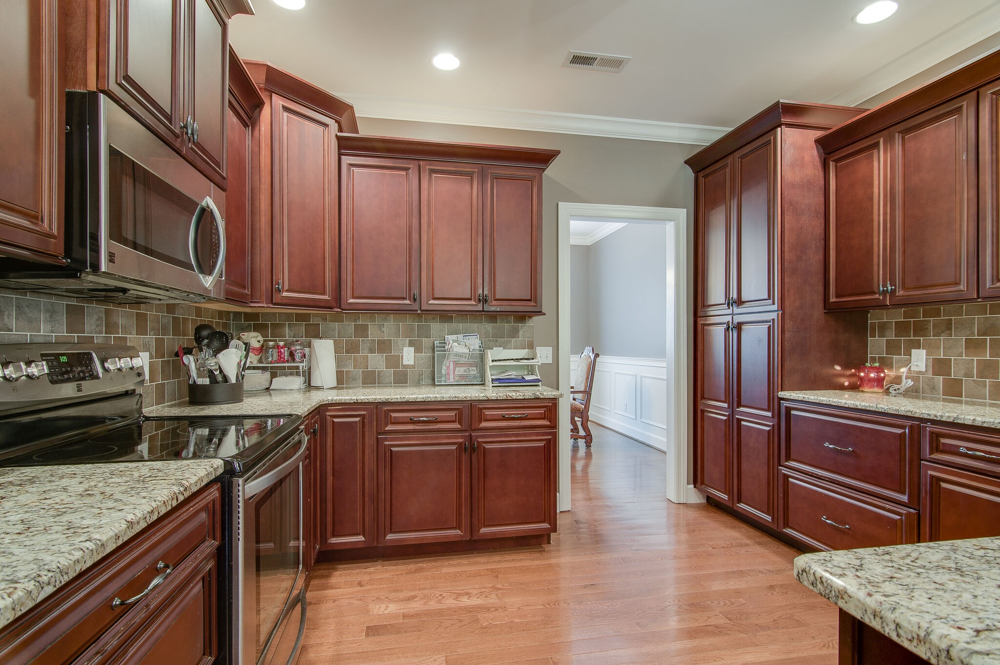 5125 Old Harding Road Franklin, TN 37064 - Photo 15 of 50 a kitchen with stainless steel appliances granite countertop a stove top oven a sink dishwasher and wooden cabinets with wooden floor