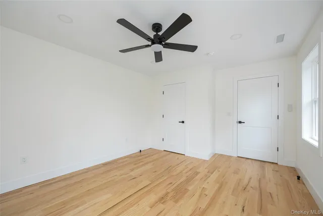 a view of empty room with wooden floor and ceiling fan