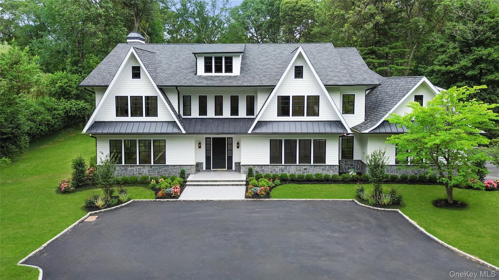 View of front of home with a standing seam roof, roof with shingles, stone siding, and a porch