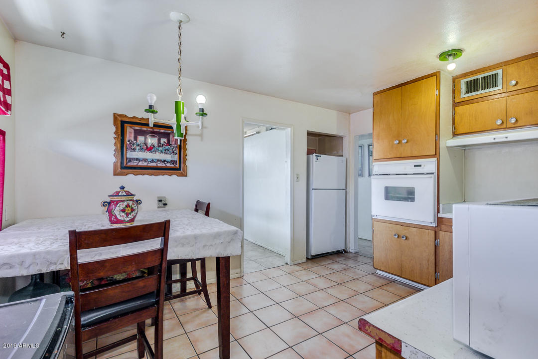 3802 West Ocotillo Road Phoenix, AZ 85019 - Photo 4 of 9 a kitchen with stainless steel appliances granite countertop a refrigerator a oven a sink a dining table and chairs with wooden floor