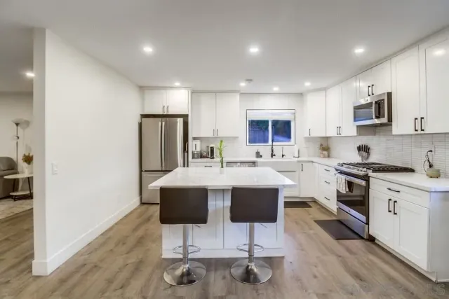 a kitchen with stainless steel appliances a stove a sink a microwave a refrigerator and cabinets